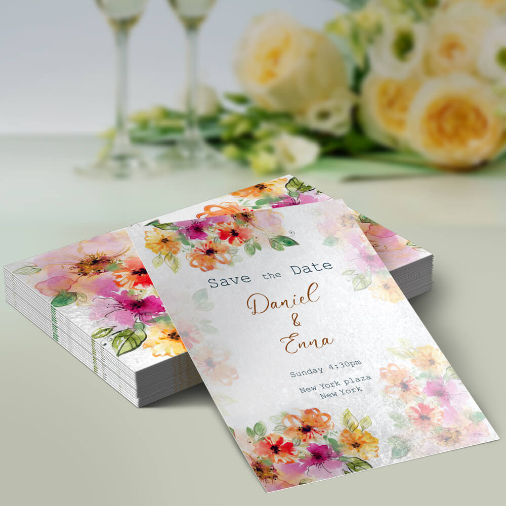 A colorful "Save the Date" card for Daniel and Emma's wedding, featuring floral decorations, set against a soft blurred background.